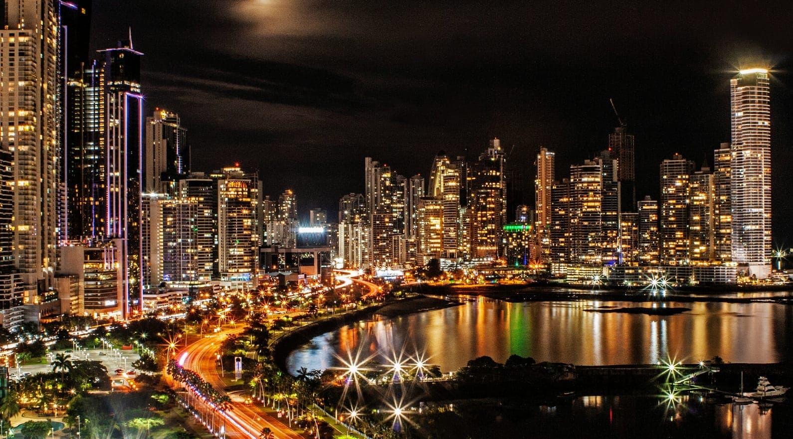 Vista nocturna de la ciudad de Panamá, con edificios iluminados y luces reflejadas en la bahía